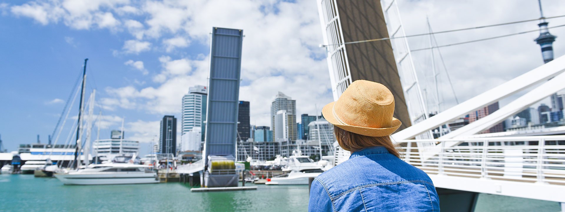 Young traveler woman in hat looking at opening Bridge in Auckland, New Zealand. City life