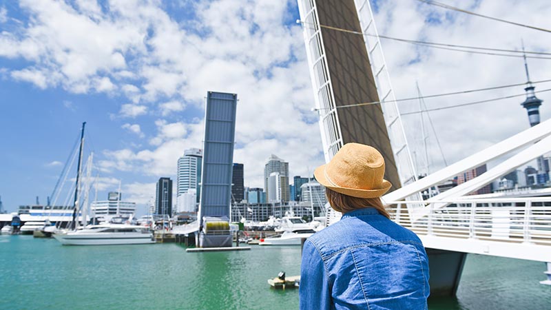 Young traveler woman in hat looking at opening Bridge in Auckland, New Zealand. City life